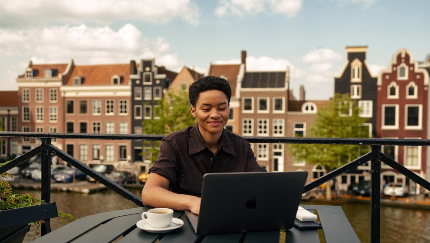 Ondernemer die ontspannen werkt vanaf een dakterras met uitzicht op de gracht